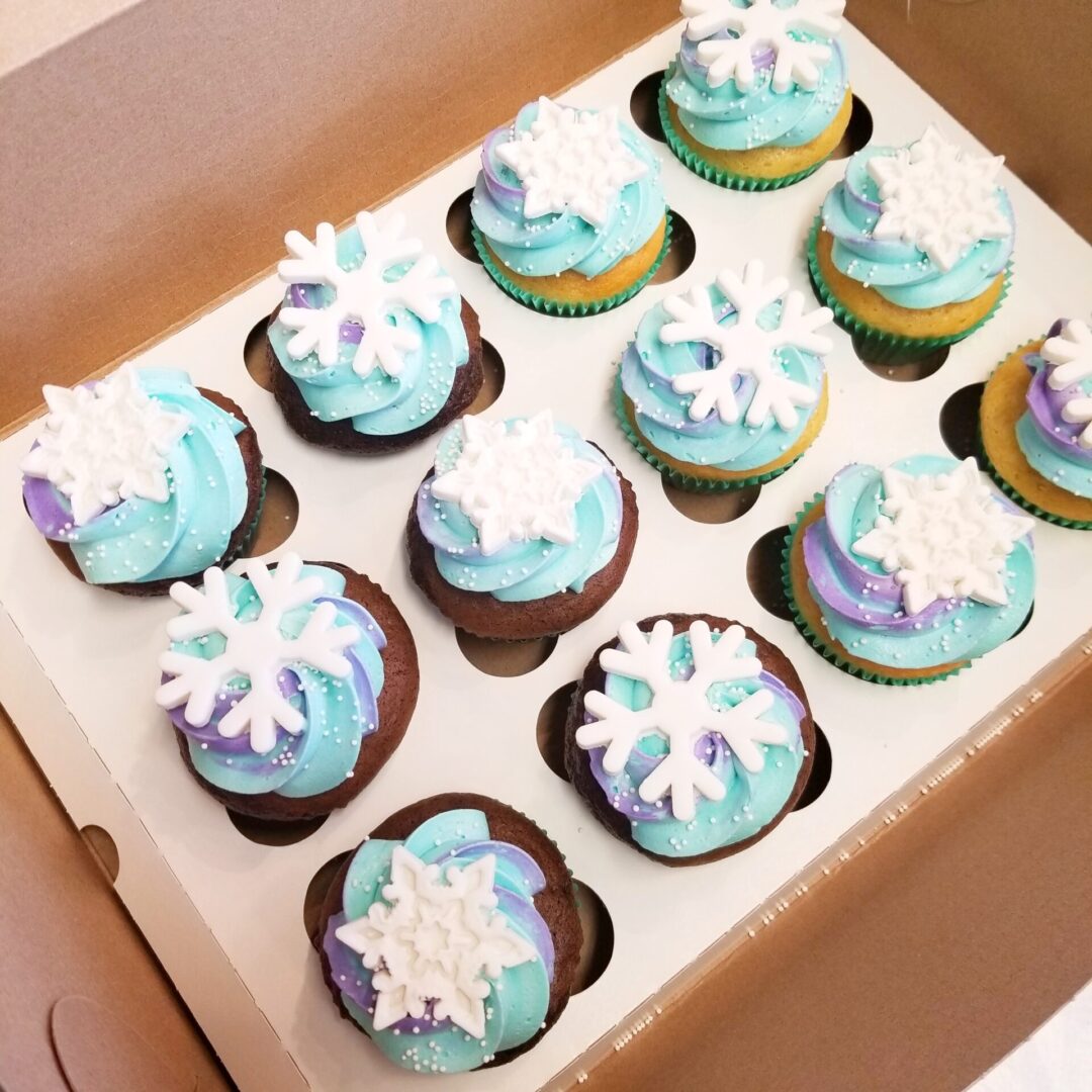 A box of cupcakes with blue frosting and white icing.