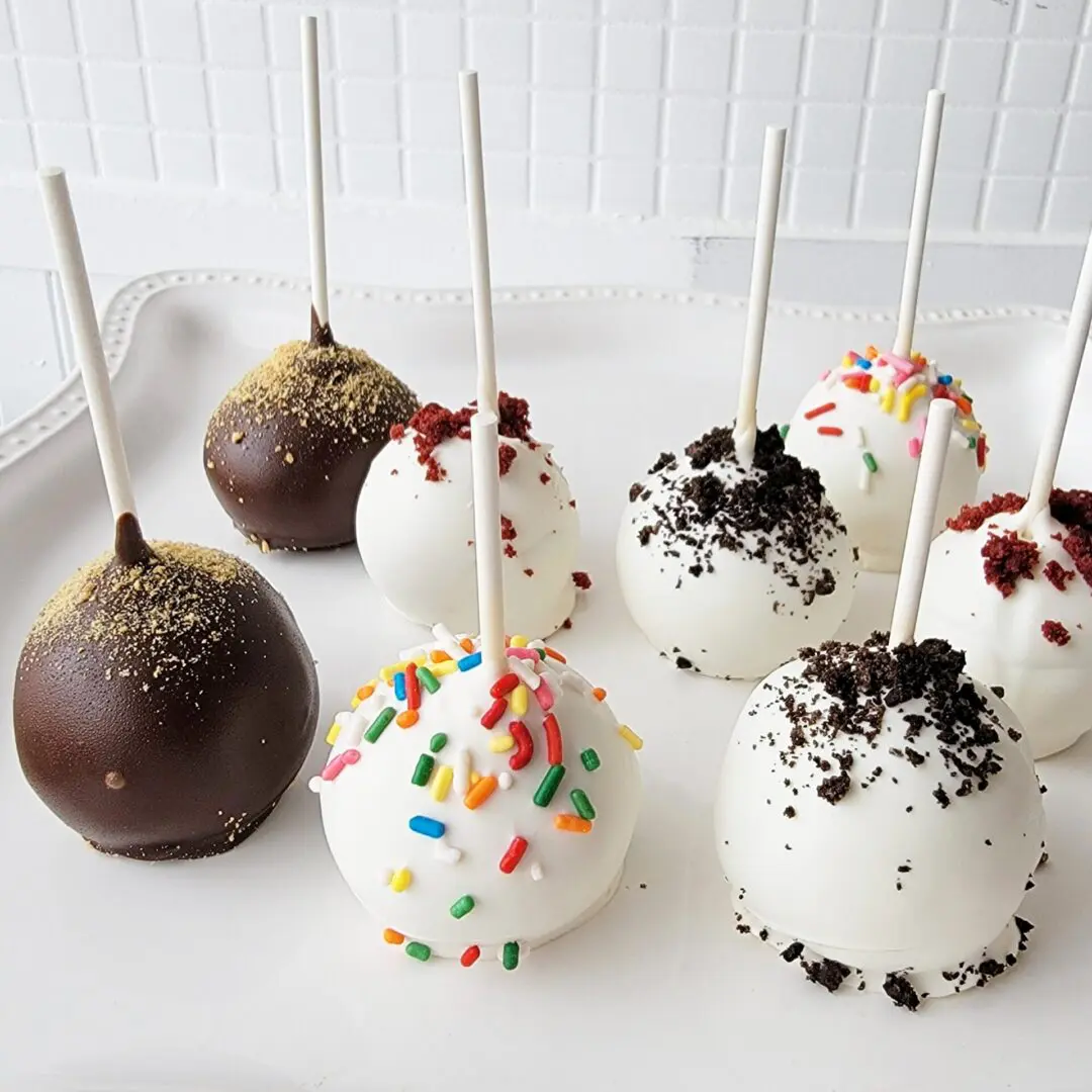 A white table topped with lots of cake pops.