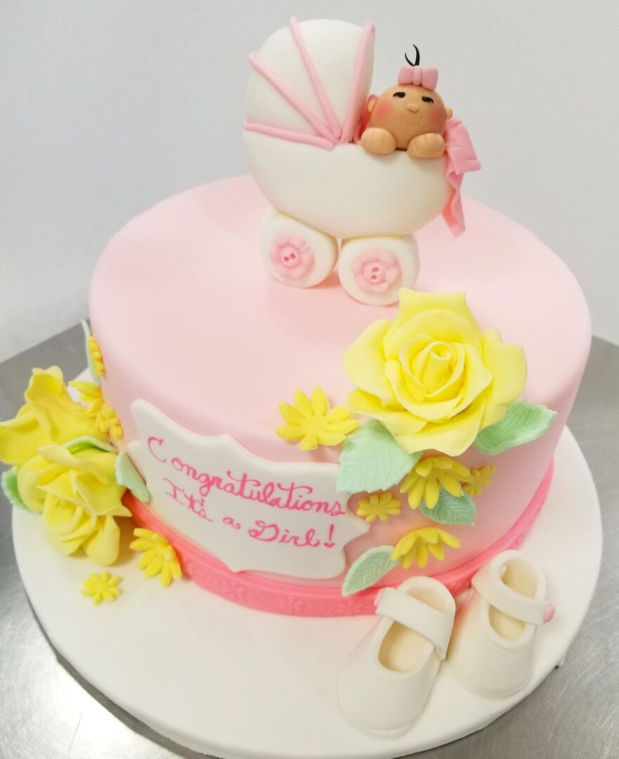 A pink cake with a stroller topper