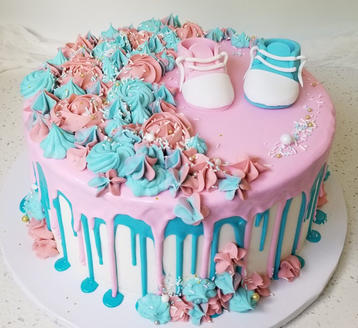 A pink and blue cake with shoes on top