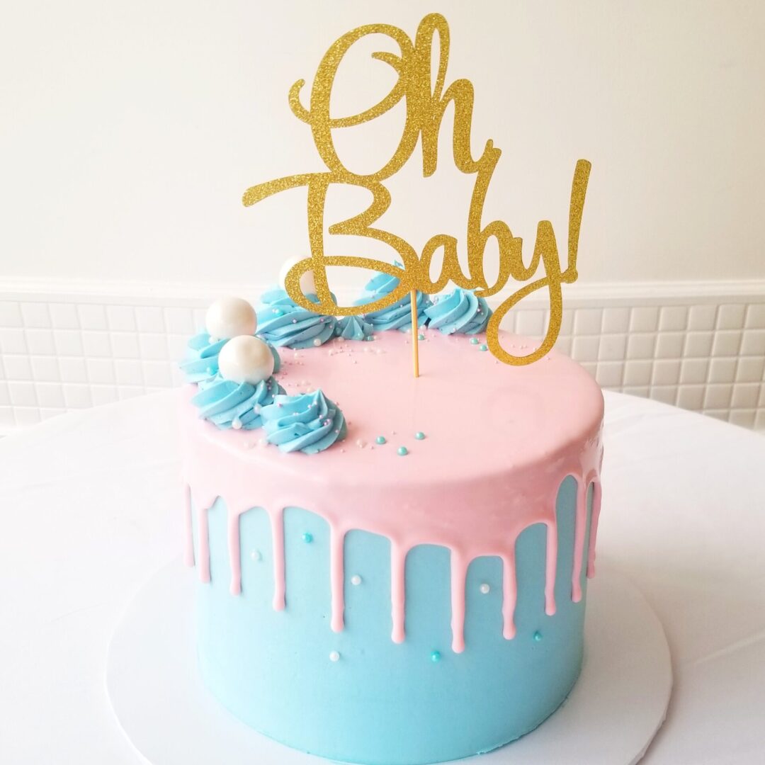 A pink and blue cake with a gold topper
