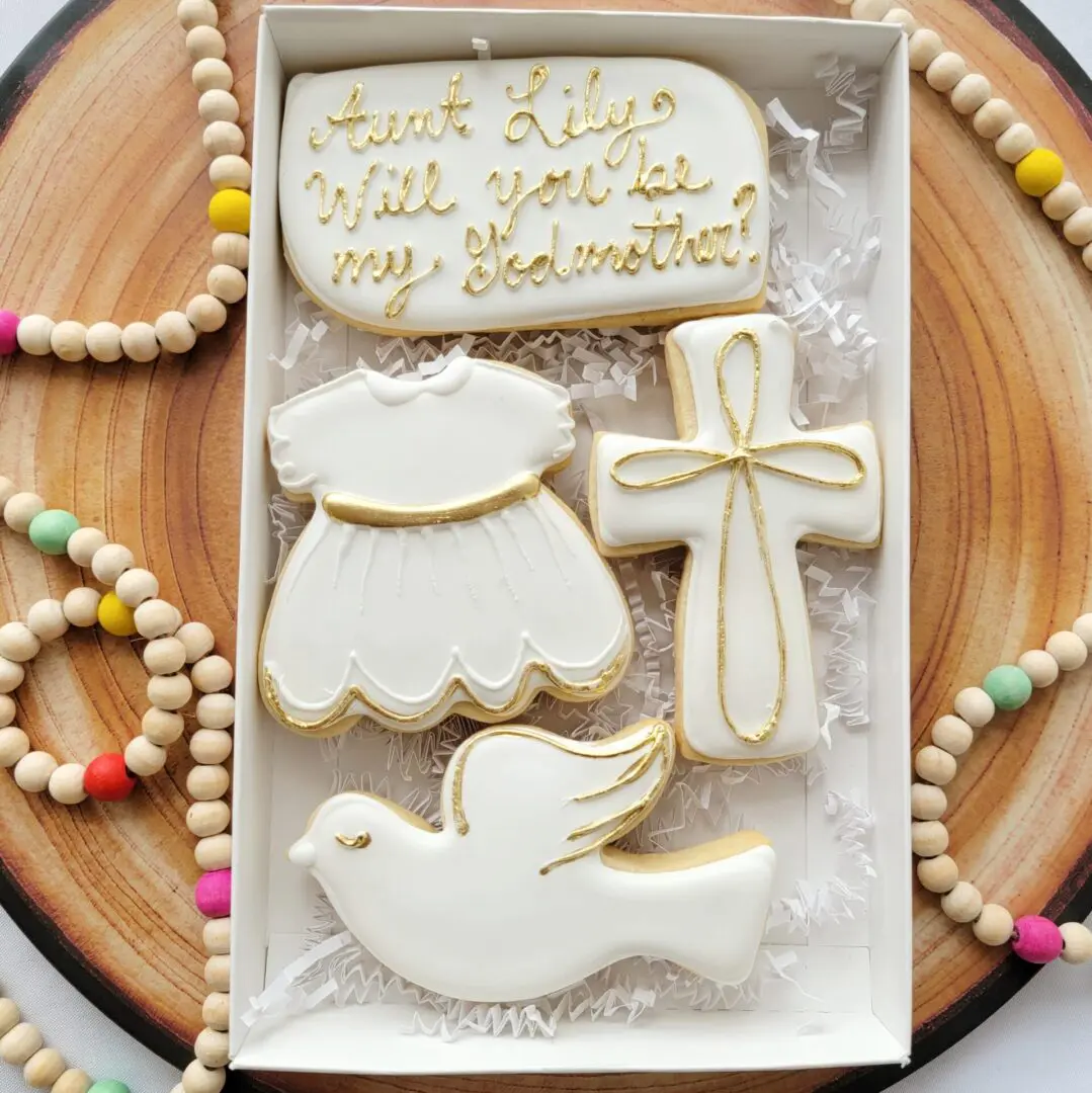 A box of cookies with a cross, dove and dress.