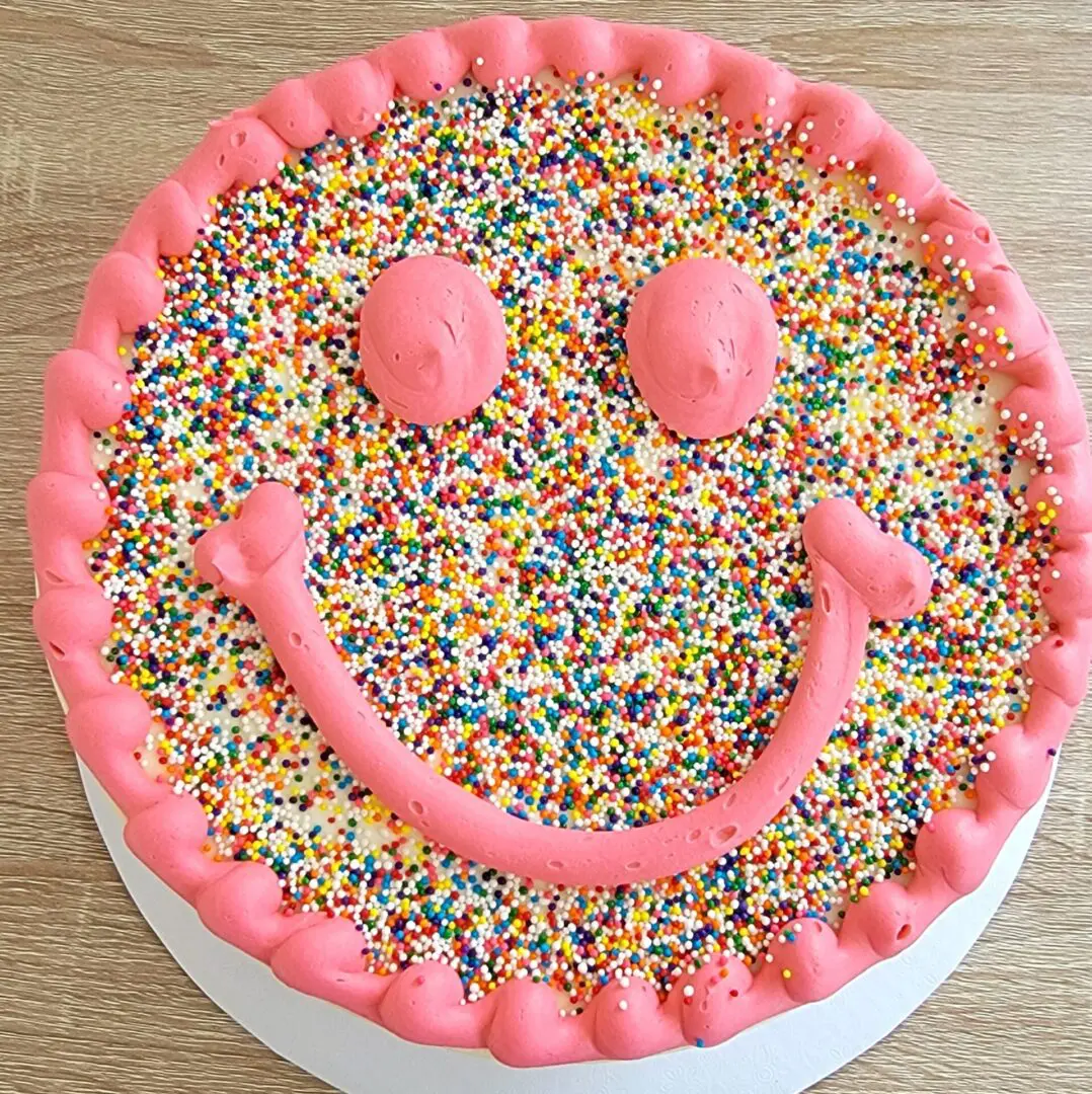 A cake with pink frosting and sprinkles on it.